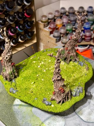 3 painted Awakened Wyldwood model trees, attached to a base that is covered in bright green flock and some small stones, to simulate a small copse in a meadow