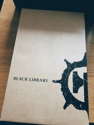 A photo of plain cardboard book packaging, featuring Black Library branding printed in black
