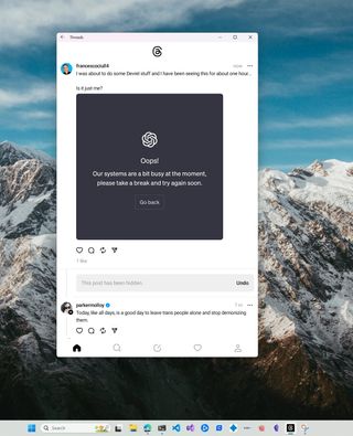 a screenshot of Threads running on Windows, with a couple of posts loaded, the Taskbar at the bottom of the screen, and the system wallpaper displayed in the background