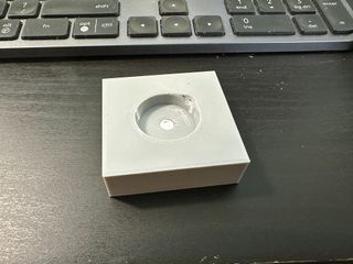 A 3D printed prototype of my 'MagPuck' jig for adding magnets beneath wargaming bases. It is a grey plastic block with a recess for a base. At the bottom of the recess is a further recess which holds a 6mm x 2mm magnet. A small area has been carved away at the edge of the base recess to allow for levering the base out